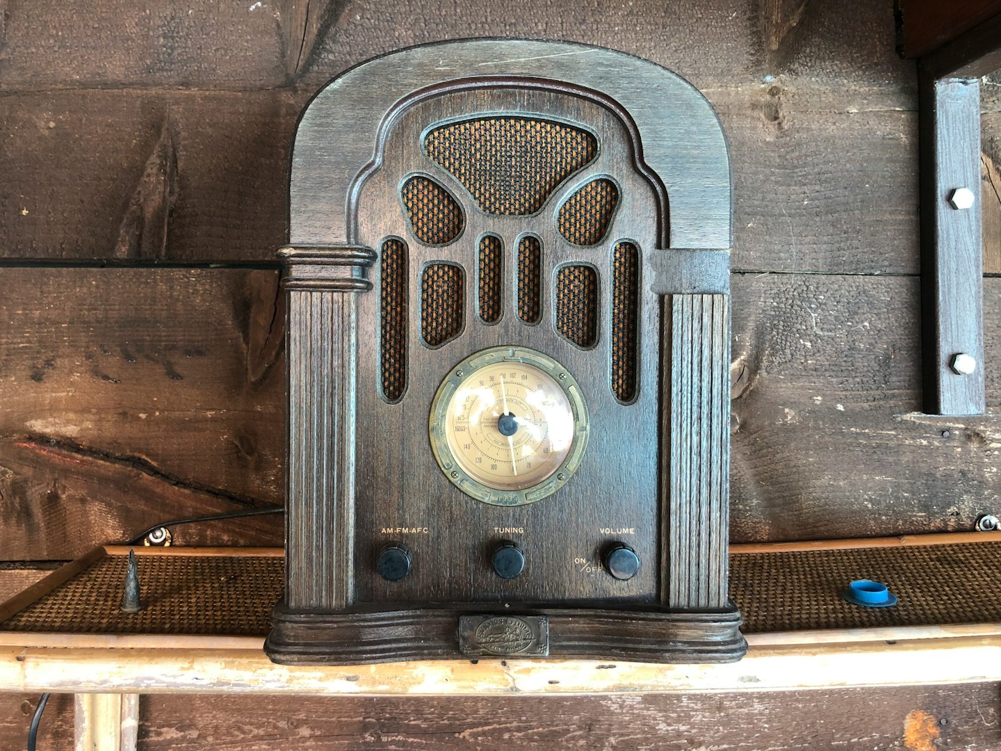 Radio antigua de madera sobre una repisa contra una pared de tablones.
