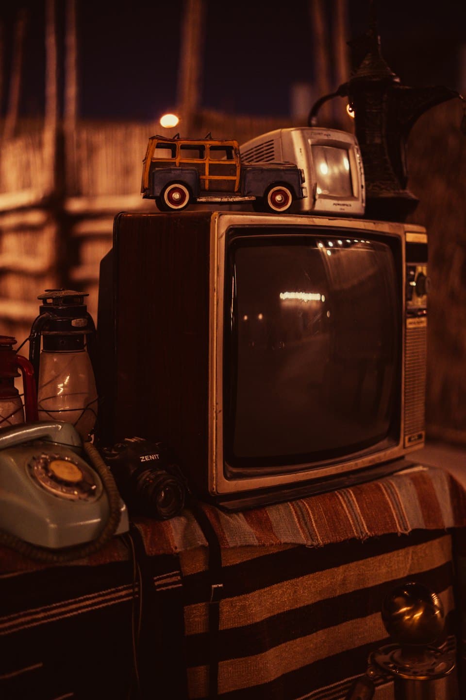 Televisor antiguo rodeado de objetos nostálgicos sobre tela a rayas.