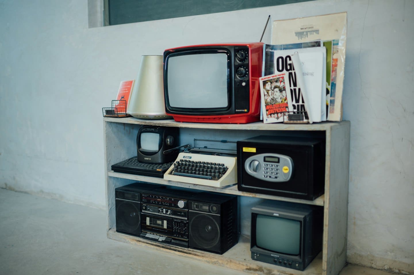 Electrónica retro y una máquina de escribir sobre estantes de madera.