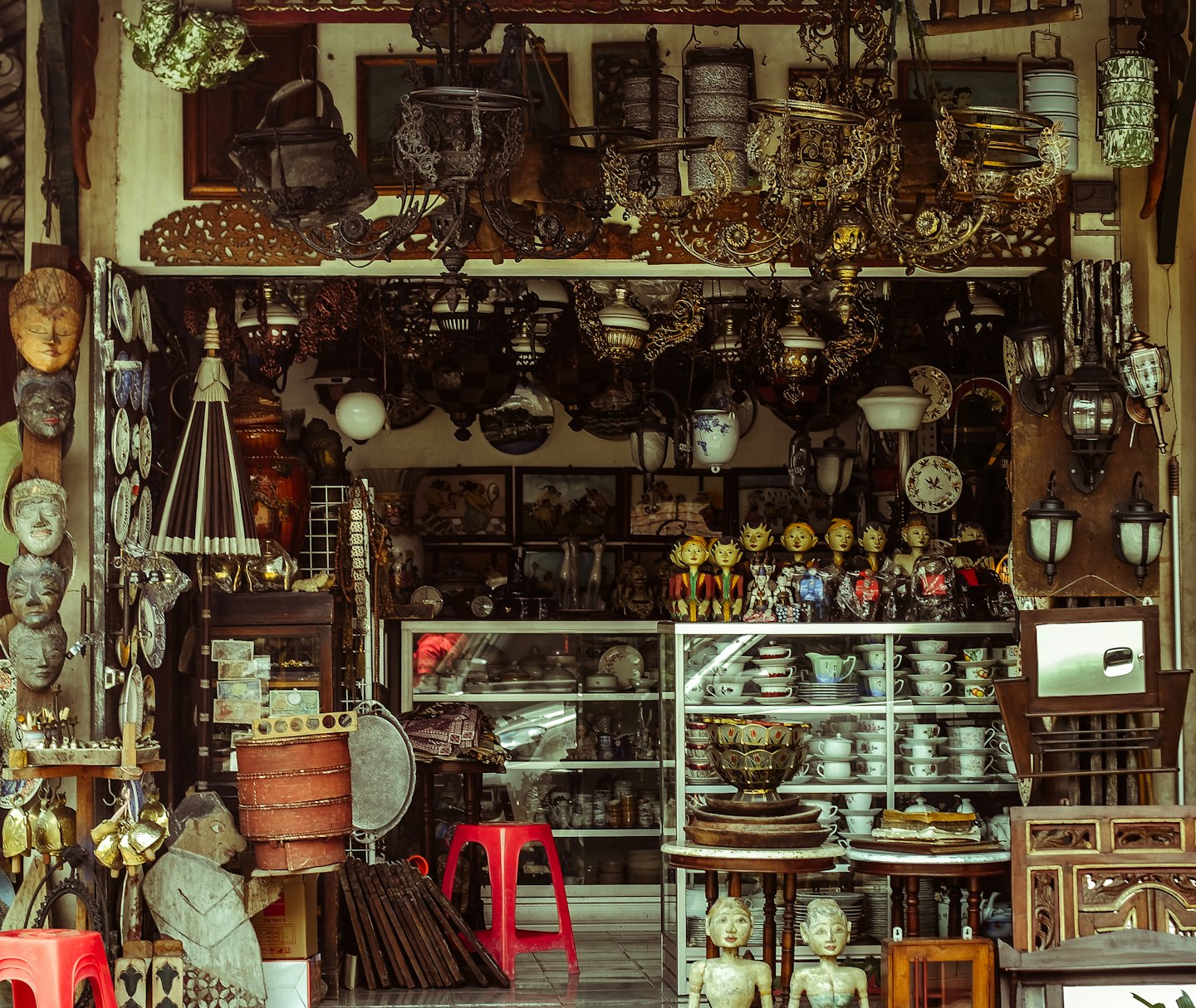 Fachada de tienda de antigüedades llena de candelabros, lámparas y decoración.